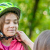 Mom adjusting girl's helmet
