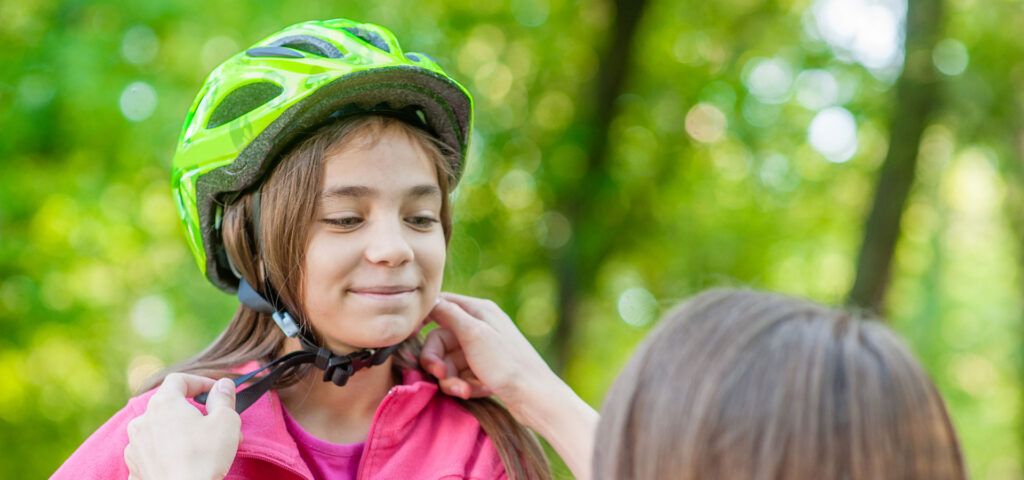 Mom adjusting girl's helmet